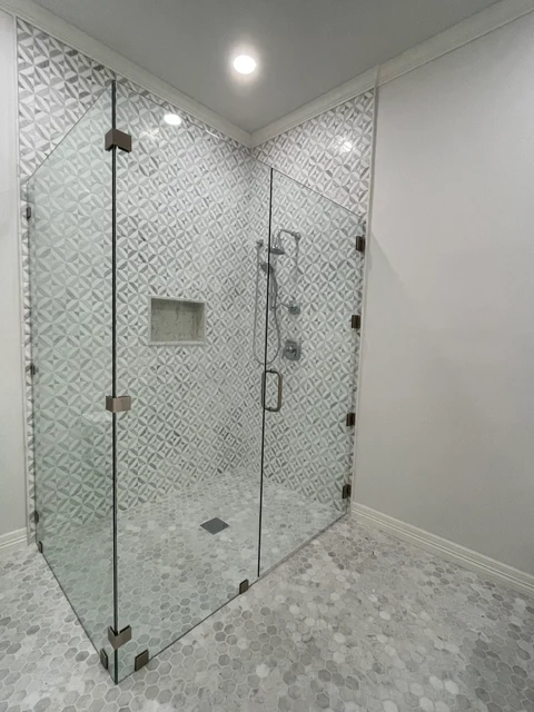 Frameless corner shower enclosure with geometric wall tile